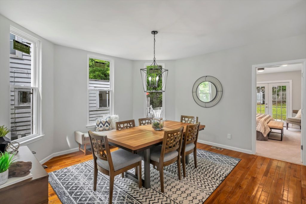 Dining room with wood table, round mirror and bay window