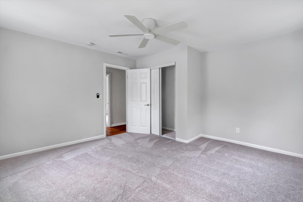 Carpeted bedroom with ceiling fan and doorway
