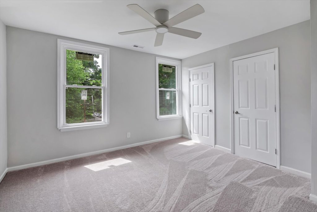 Carpeted bedroom with two windows and closet door