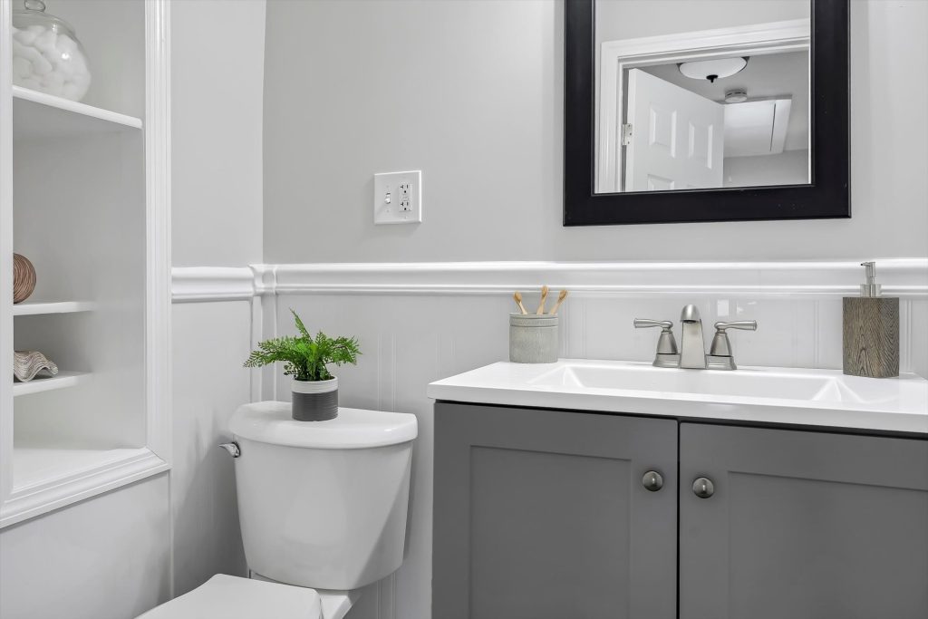 Bathroom with gray vanity, framed mirror and built-in shelving