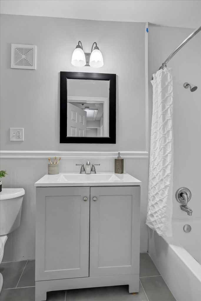 Bathroom with gray vanity, black framed mirror and shower curtain