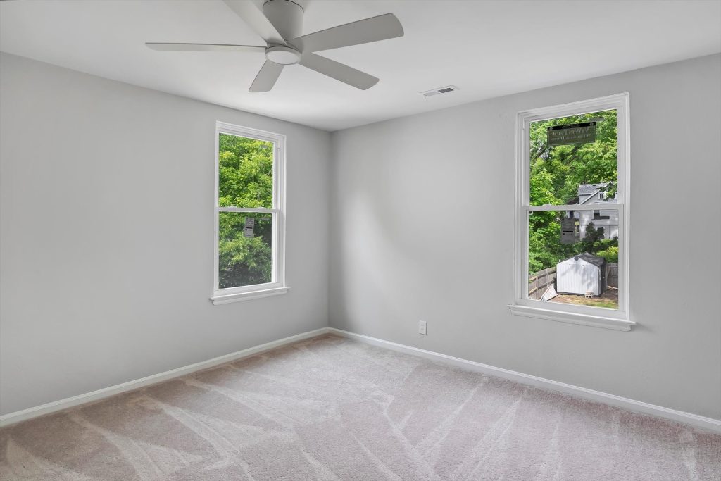 Carpeted bedroom with ceiling fan and two windows