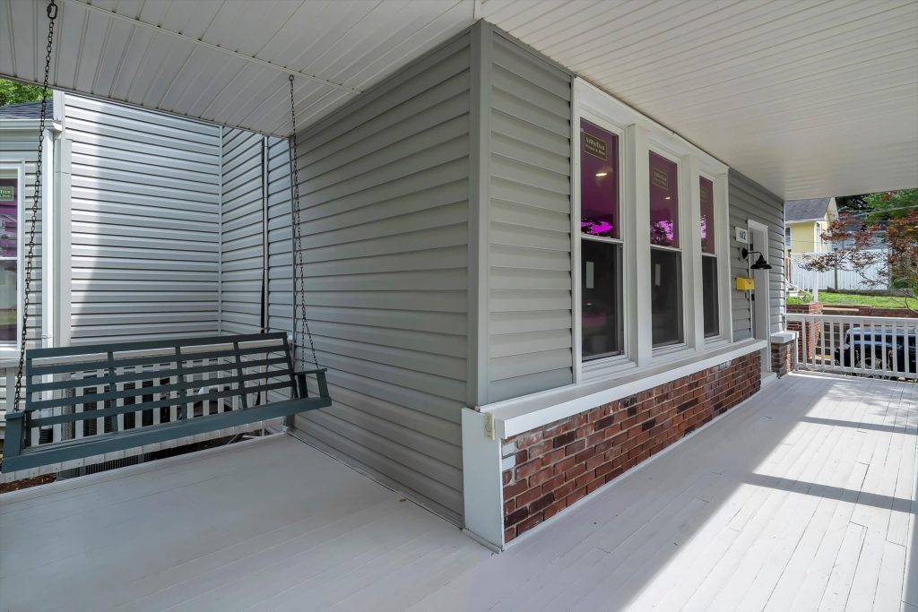 Side porch with hanging bench and brick skirt