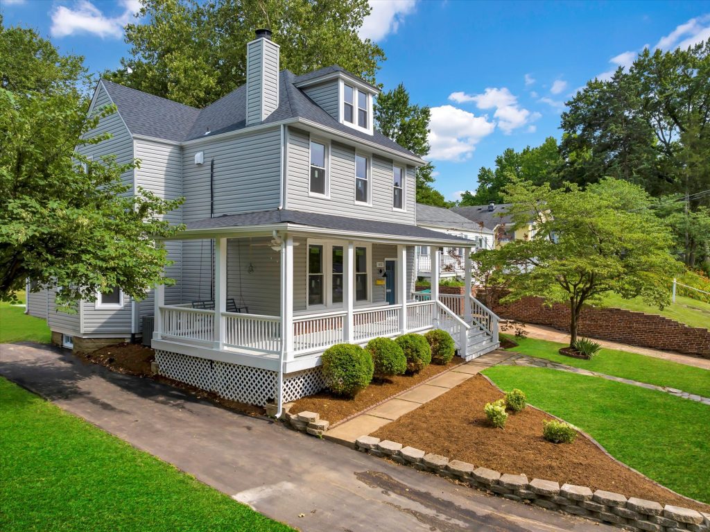 Grey two story house with wraparound porch and lawn