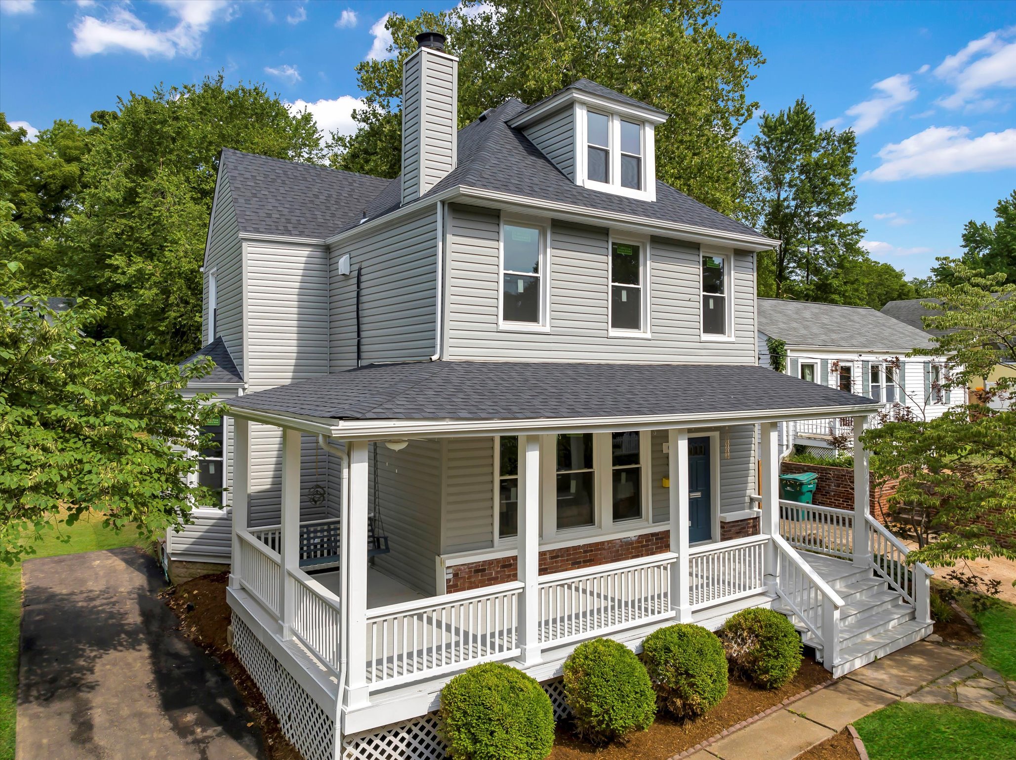 Grey two story house with dormer and wraparound front porch