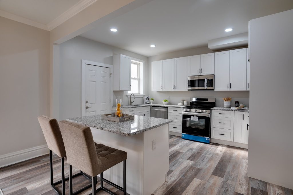 Kitchen with white cabinets, granite island and two stools