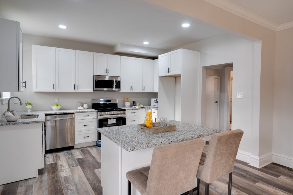Kitchen with white cabinets, stainless range and island seating
