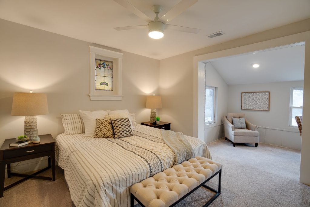 Bedroom with upholstered bench and stained glass window