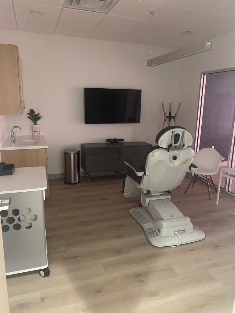 Clinic treatment room with examination chair and wall mounted screen