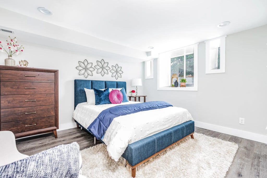 Bedroom with navy upholstered bed and wood dresser