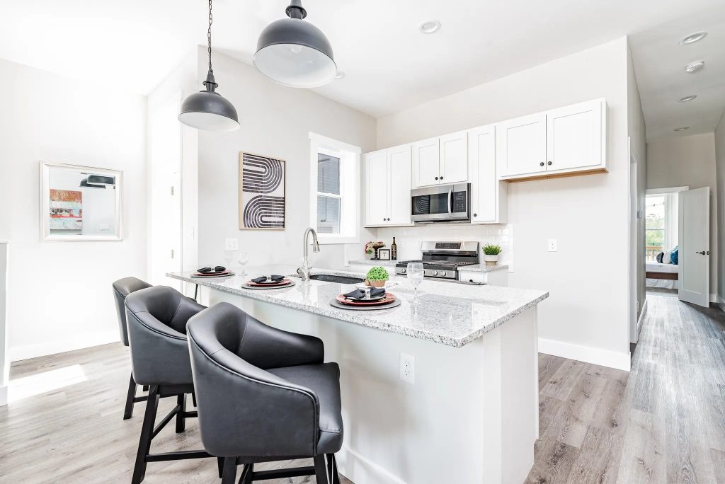 Kitchen with white cabinets, granite island and dome pendants