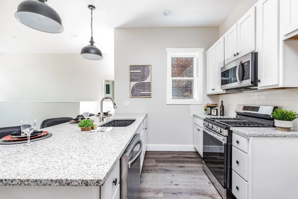 Kitchen with white cabinets, granite island and stainless range