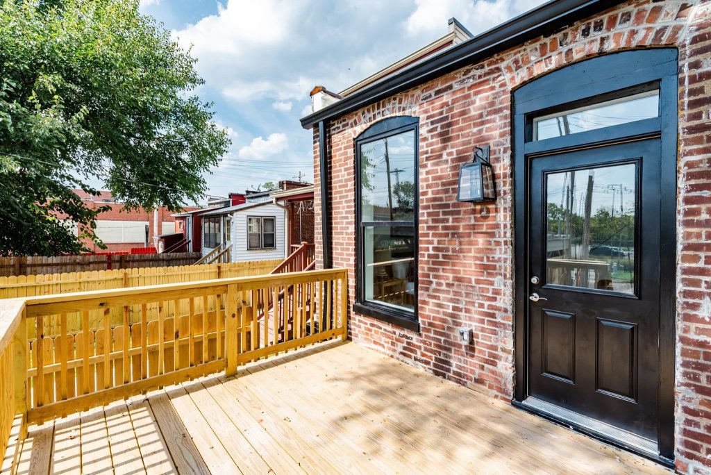 Rear deck with black door and exposed brick wall