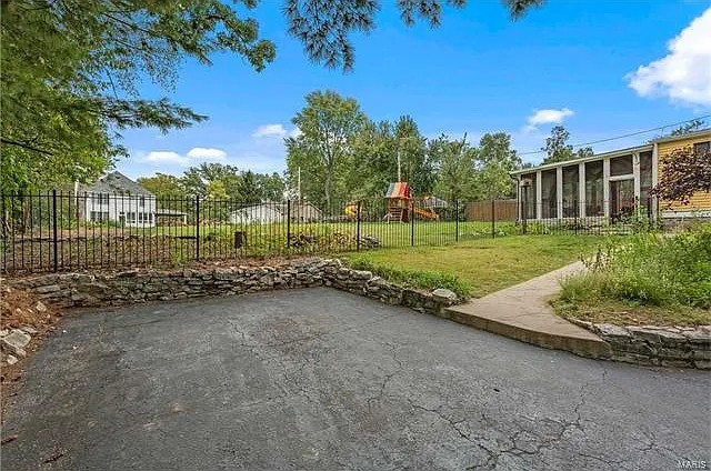 Cracked asphalt parking area and stone retaining wall before work began