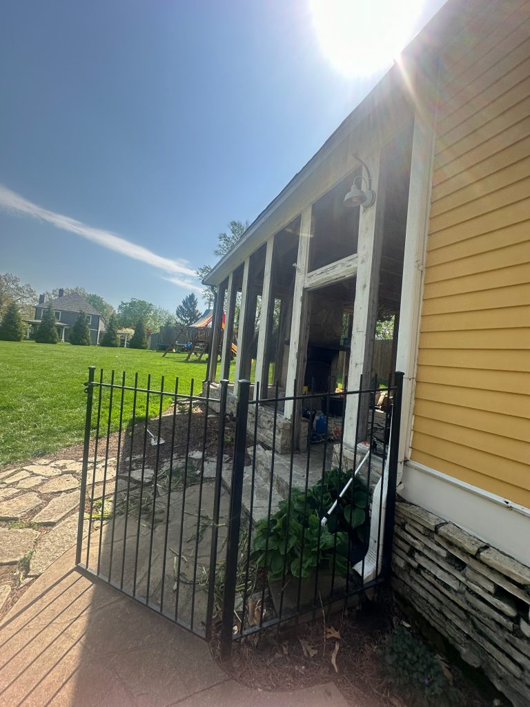 Side of the original house along the iron fence and stone base