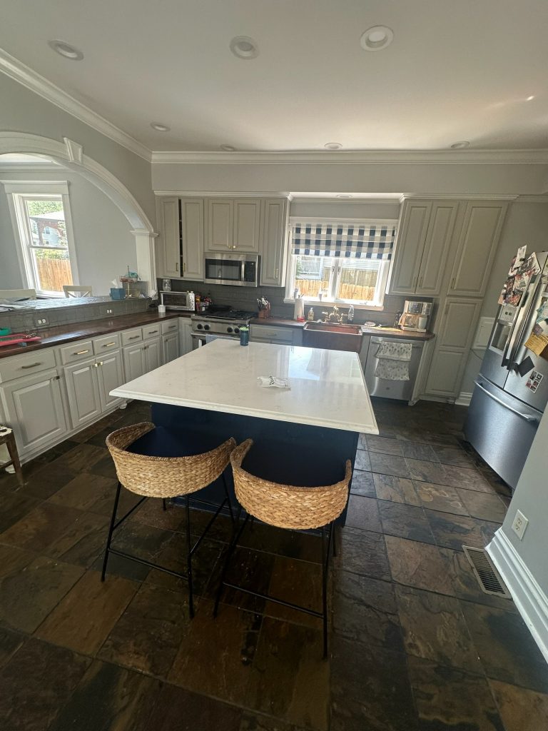 Original kitchen with a slate floor, white cabinetry and an arched opening