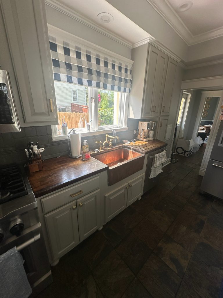 Original kitchen sink wall with a farmhouse sink and dark countertop