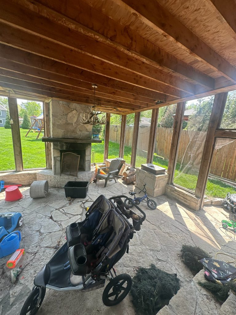 Original screened porch showing the beamed ceiling and stone fireplace