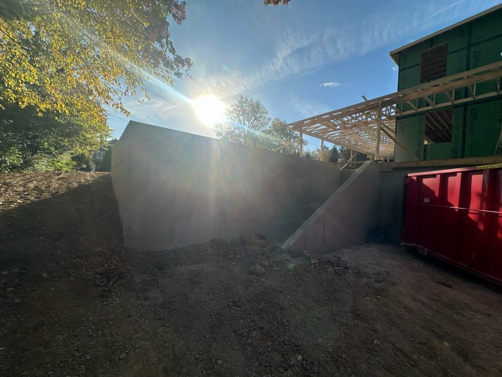 Excavated ground at the side of the house beside the dumpster