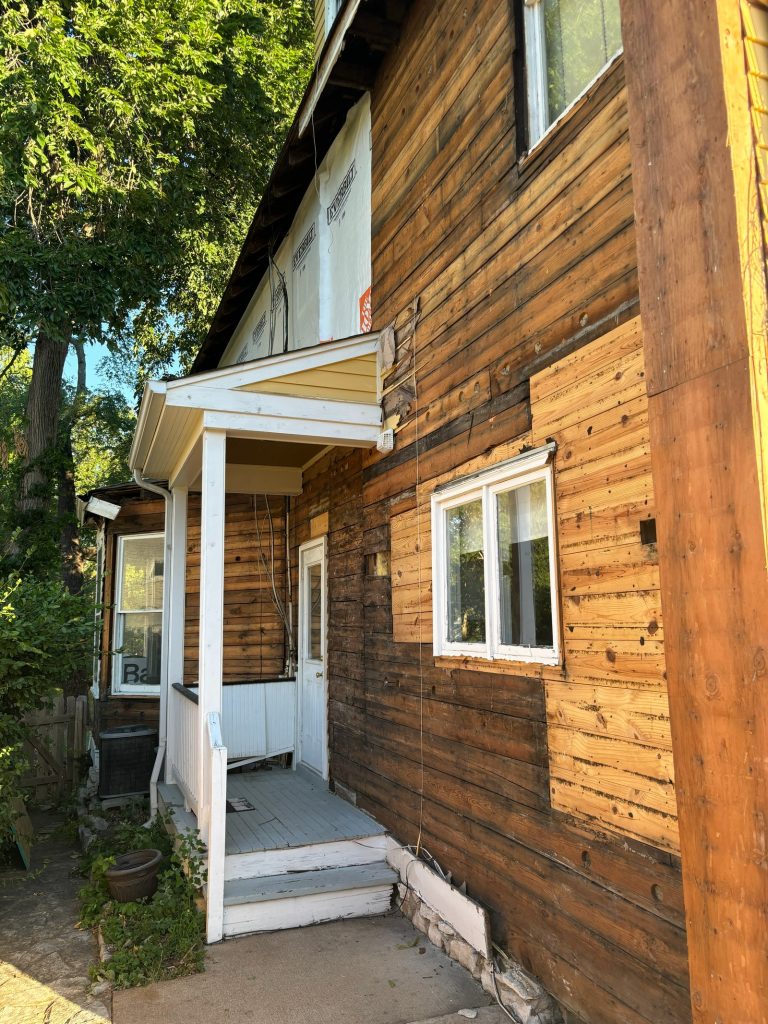 Bare original wood siding beside the front entry