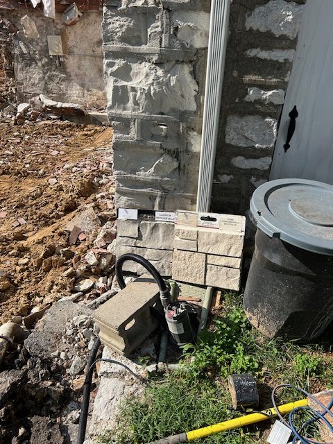 Excavation exposing the original stone wall beside new services