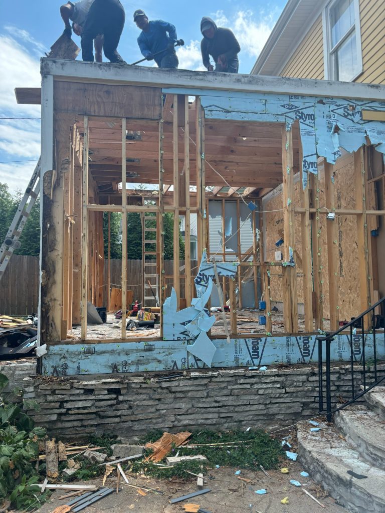 Framing the new addition, with carpenters working on the deck above