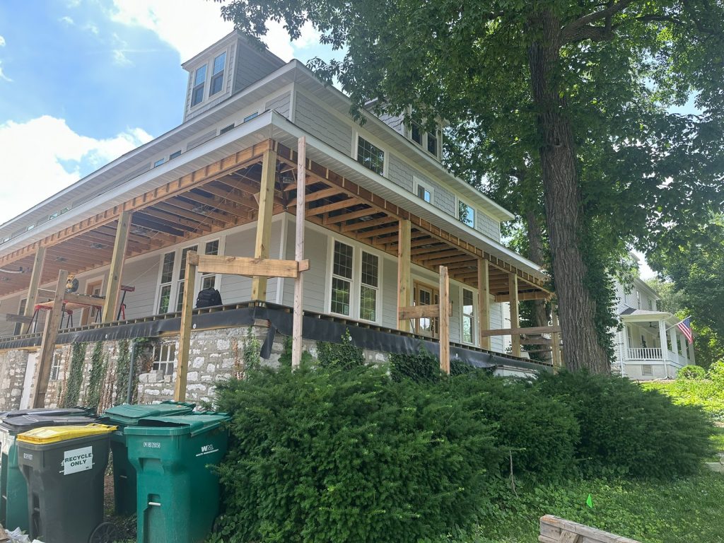New porch framing along the rear elevation above the original stone foundation