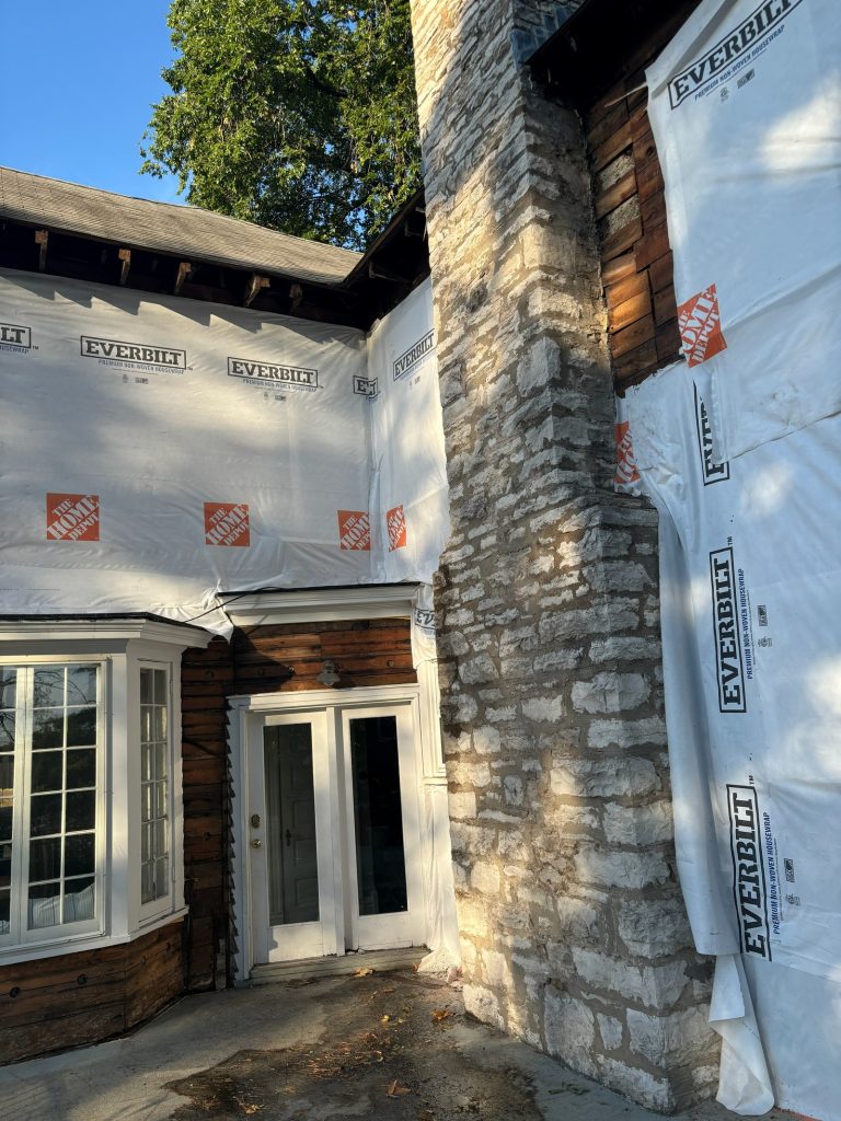 Housewrap going on beside the retained original stone chimney
