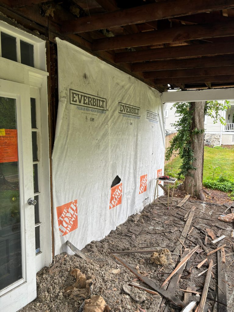 Wrapped porch area with demolition debris below
