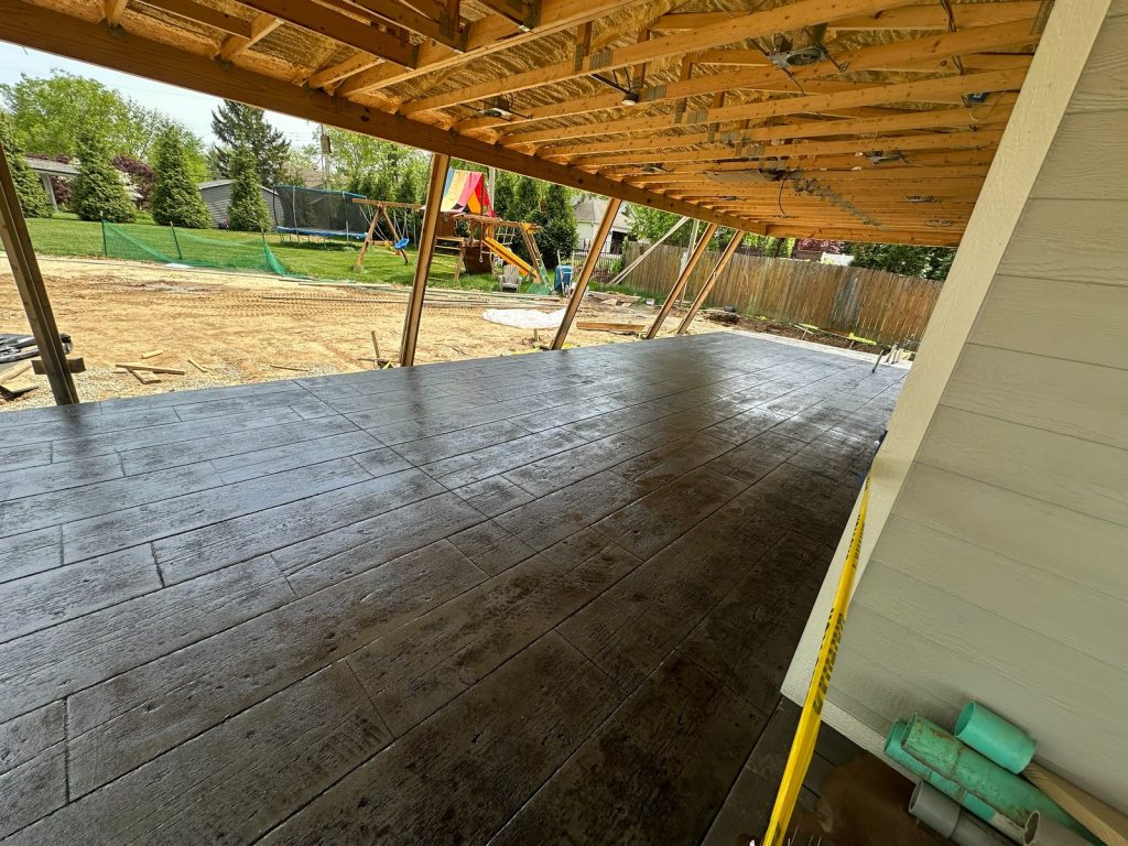 Stamped concrete patio beneath the new covered porch framing