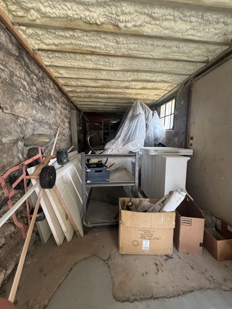 Original stone foundation wall in the basement with new spray foam insulation above