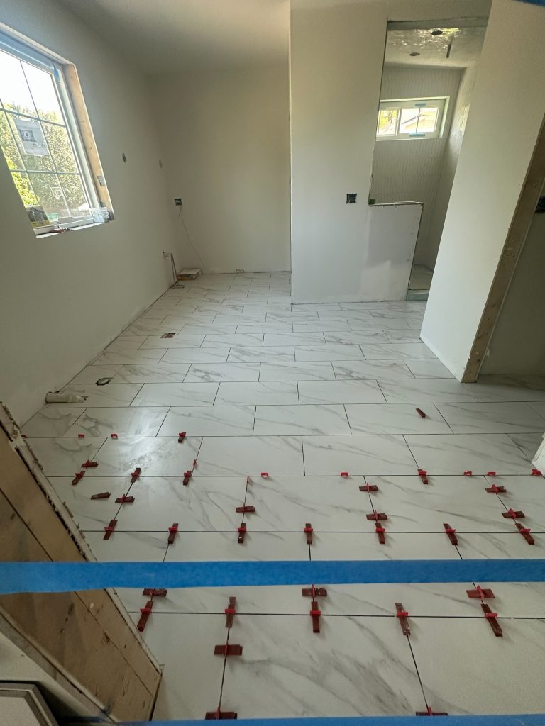 Marble-look floor tile being laid in the hallway