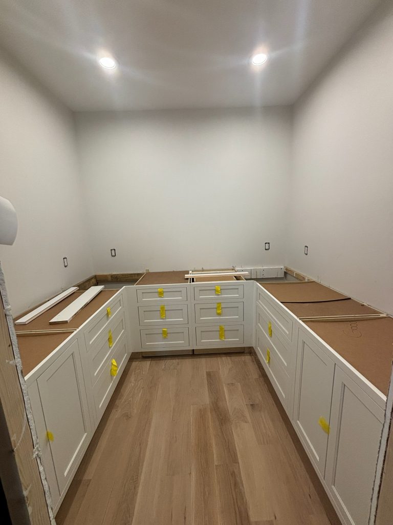 Utility room with new white cabinetry and protected countertops