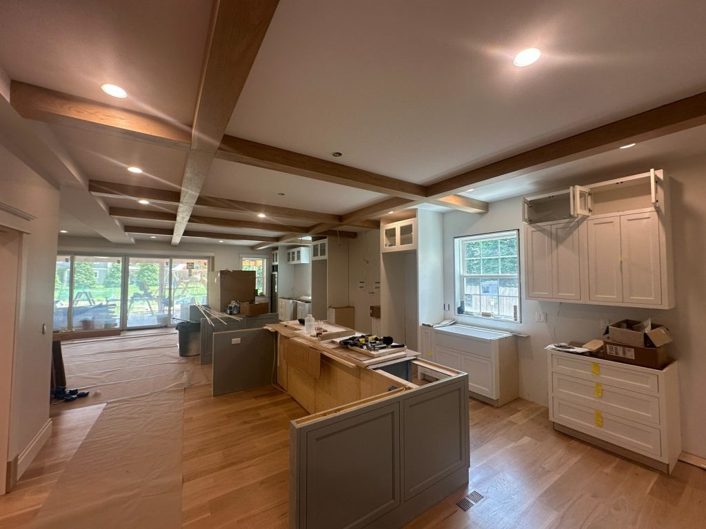 Kitchen and living space with beams in place and cabinetry going in