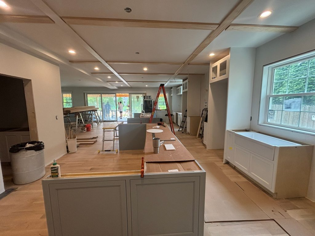 Kitchen and great room during finish work, with the island framed and floors protected