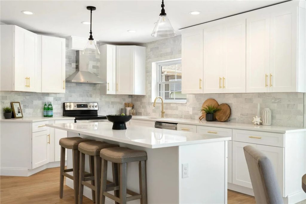 Kitchen with white cabinets, island stools and range hood