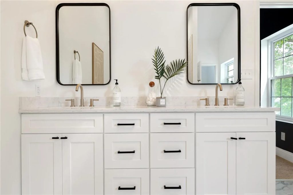 Double vanity with black framed mirrors and gold faucets