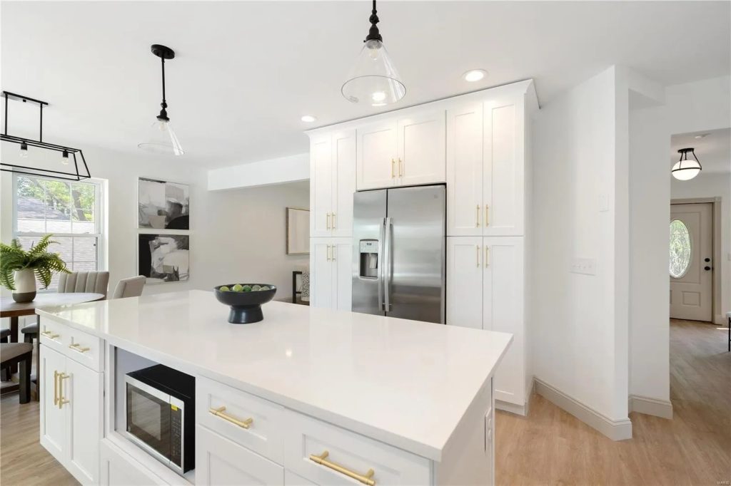 Kitchen island with stainless refrigerator beyond