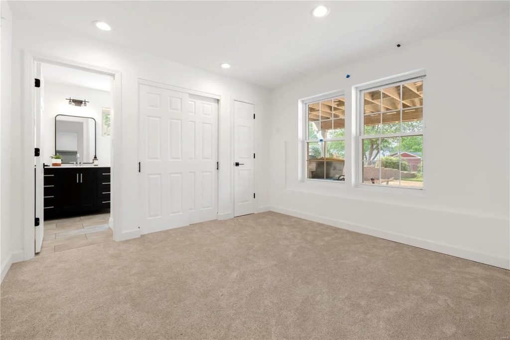 Carpeted bedroom with closet doors and window