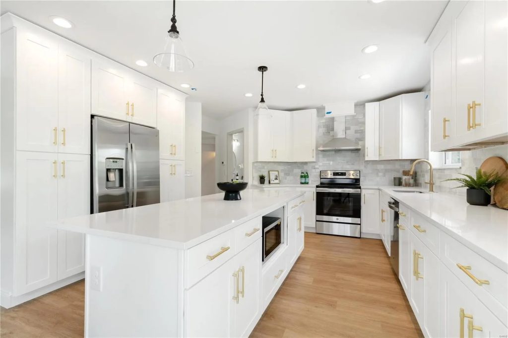 Kitchen with white cabinets, quartz island and stainless range