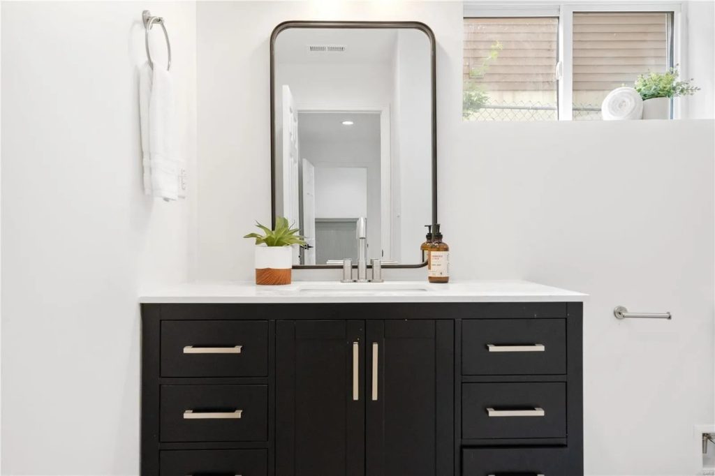 Bathroom with dark vanity and framed mirror
