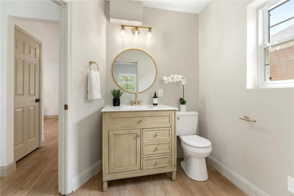 Powder room with wood vanity and round mirror