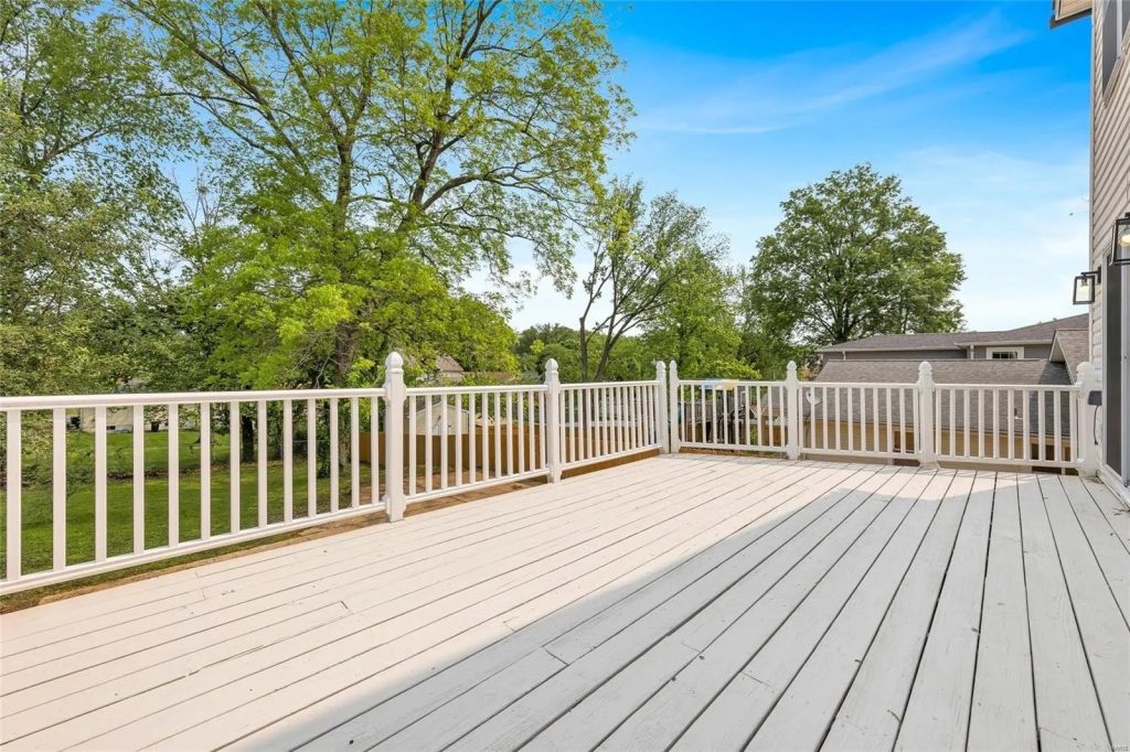 Rear deck with white railings and mature trees
