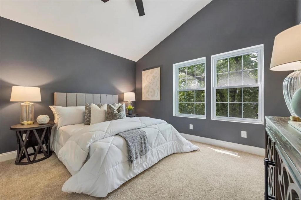 Bedroom with dark accent wall and vaulted ceiling