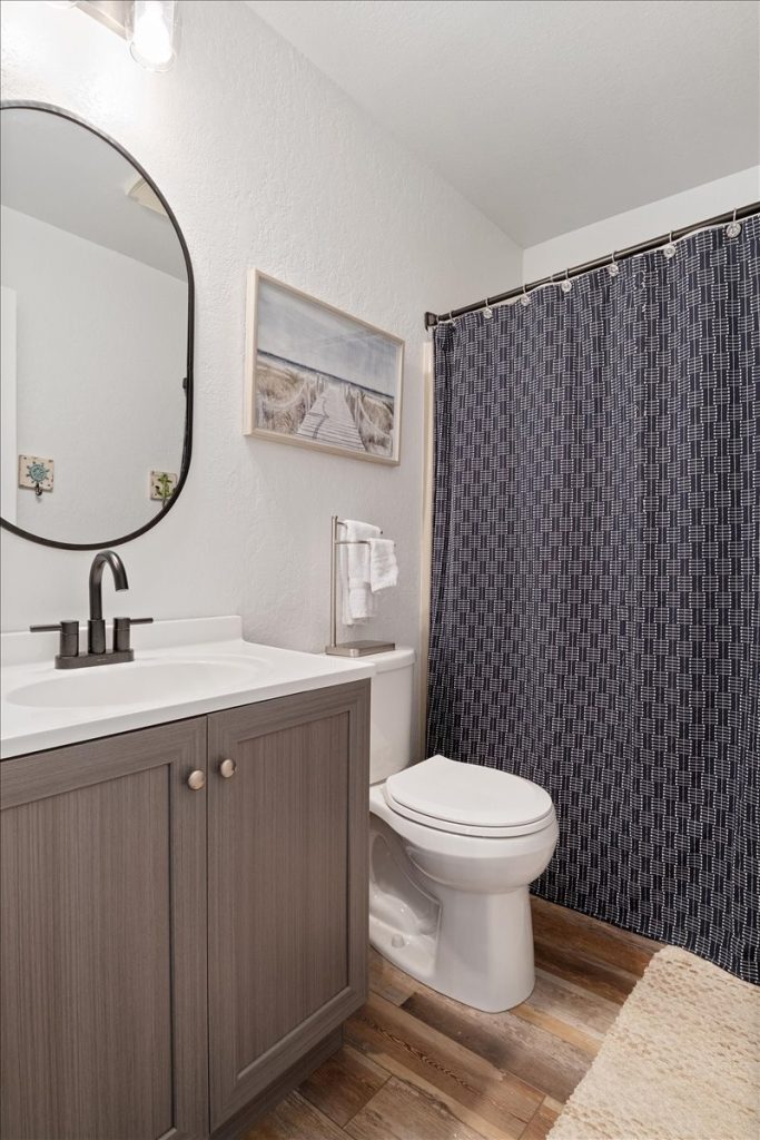 Bathroom with wood vanity and patterned shower curtain