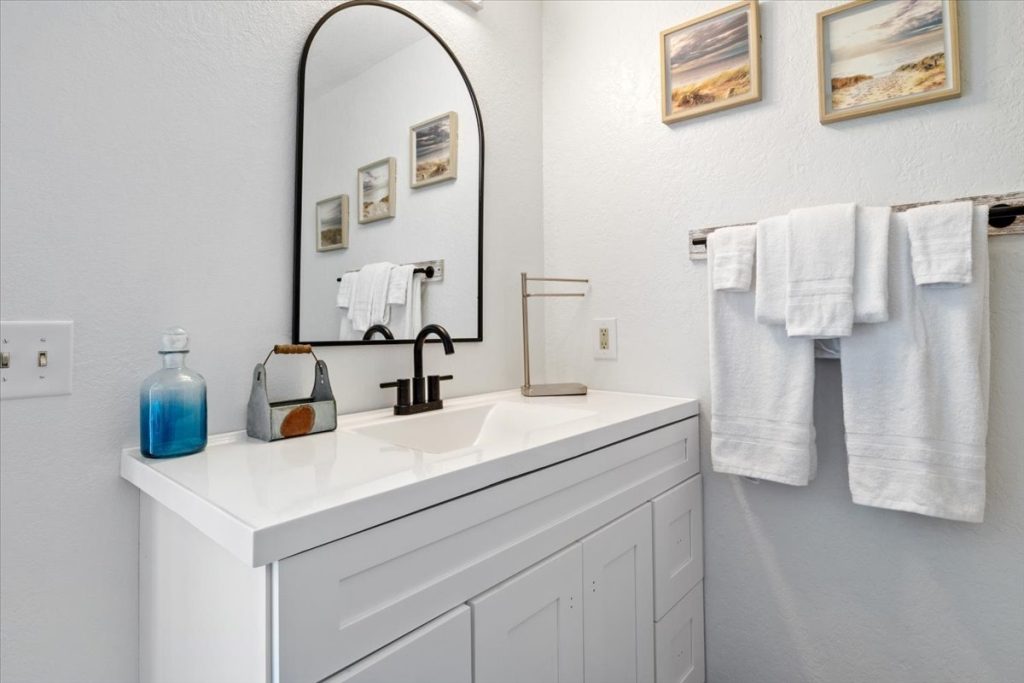Bathroom vanity with arched mirror and coastal prints