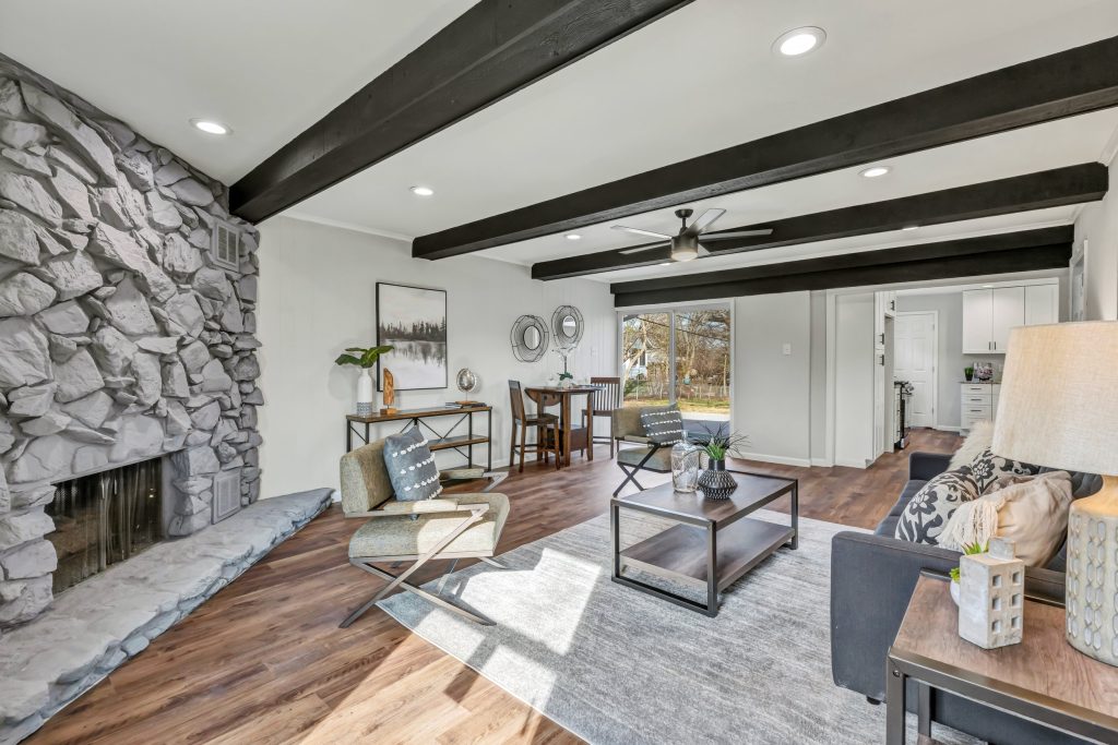 Stone fireplace with exposed beams and dining area beyond