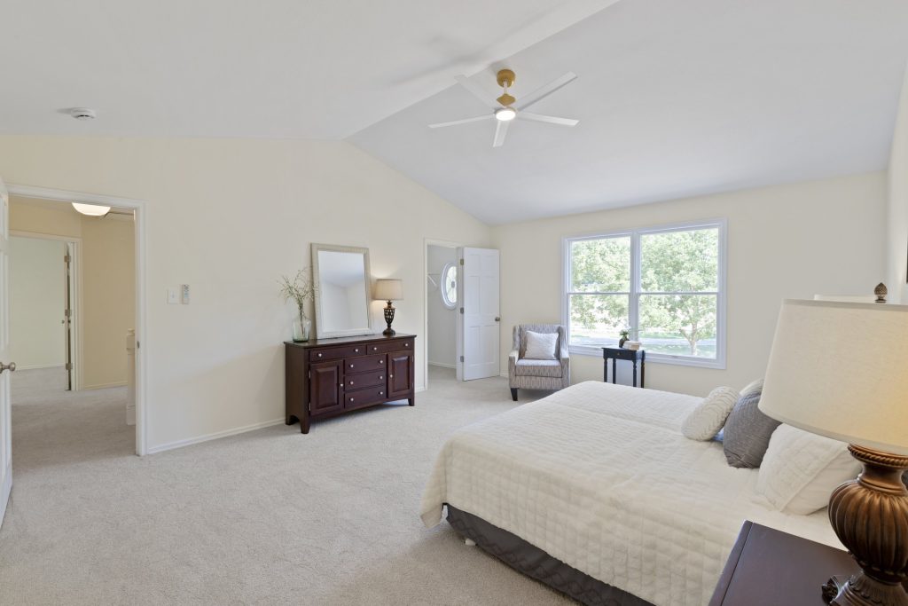 Primary bedroom with vaulted ceiling and dresser