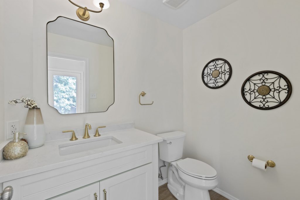 Powder room with white vanity and framed mirror