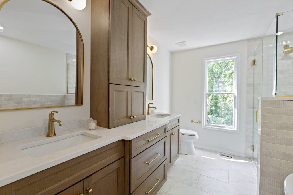 Bathroom with wood vanity, tower cabinet and arched mirror